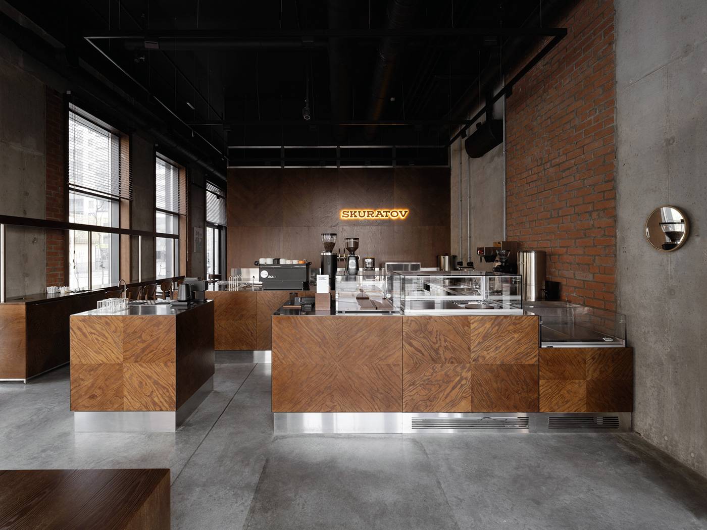Skuratov coffee roasters (Kazan) — 입구에서 본 전체. 원목 바, 벽돌 기둥, 콘크리트 바닥