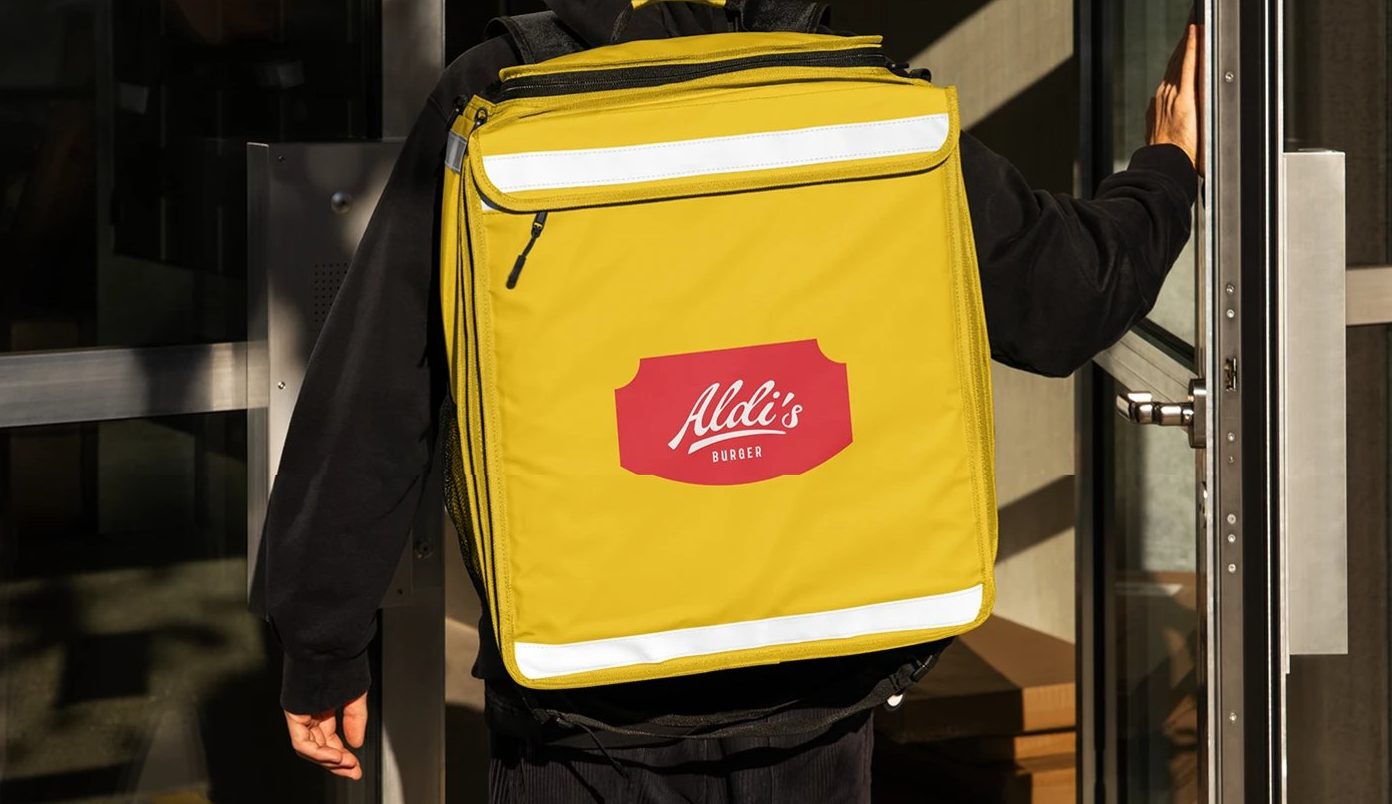 Aldi's Burger Visual Identity — 배달 가방. 노란 면에 빨간 배지 하나