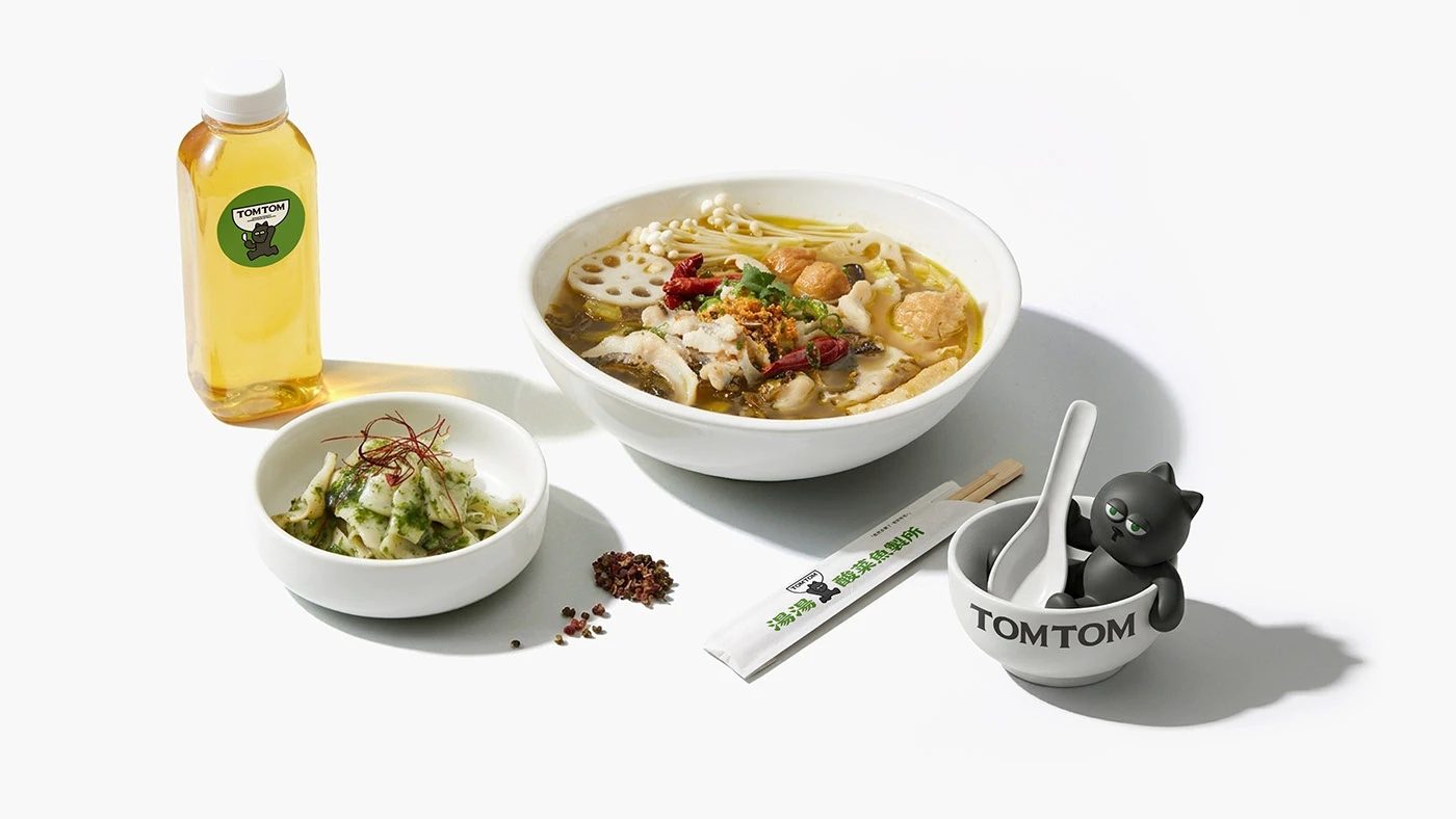 TOMTOM — 생선탕 한 그릇과 곁들이 반찬, 그릇 옆에 앉은 검은 고양이 인형